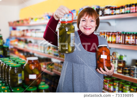 Woman choosing preserved vegetables 73339895