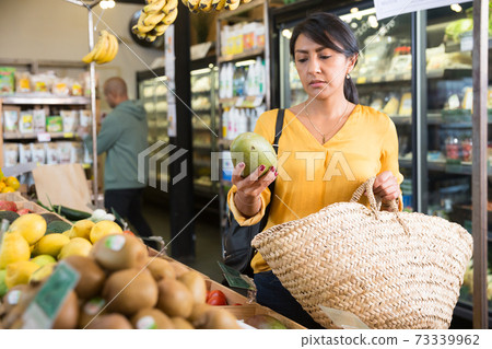 Female consumer choosing mango in supermarket 73339962