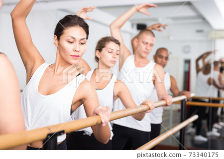 Asian girl in leotard training in ballet class with other dancers Asian girl in leotard training in ballet class with other dancers 73340175