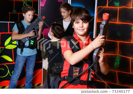 Portrait of preteen boy with laser pistol posing in laser tag labyrinth 73340177