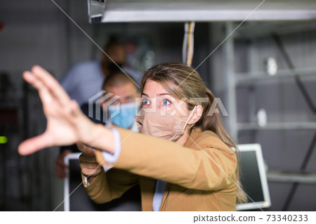 Woman looking for way out of quest room with her business colleagues in medical masks 73340233