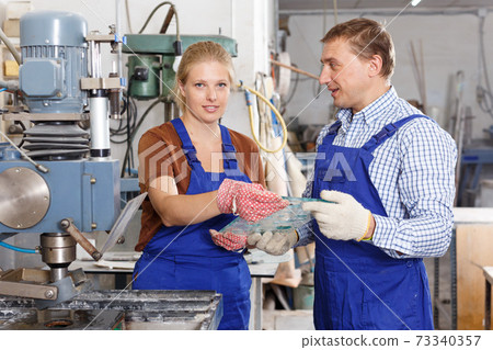 Female worker with foreman working on glass drilling machine Female worker with foreman working on glass drilling machine 73340357