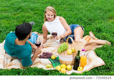 Smiling couple is lying with wineglasses and talking 73340524