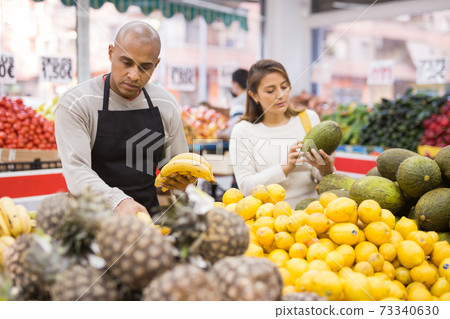 Spanish employee in fruits store with pineapples 73340630