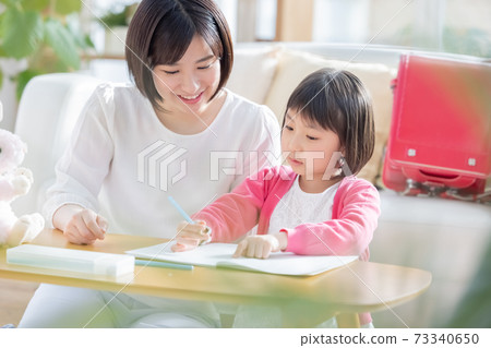 Family image Girl doing homework with mom Family image Girl doing homework with mom 73340650