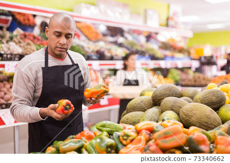 Spanish employee in vegetable store with peppers 73340662