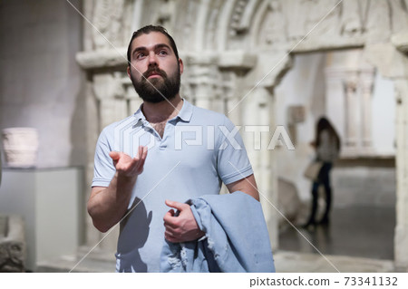 Man looking at stone architectural elements in historical museum hall Man looking at stone architectural elements in historical museum hall 73341132