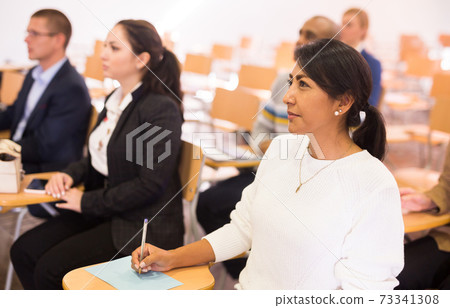 Focused Latina listening to speaker at business conference Focused Latina listening to speaker at business conference 73341308