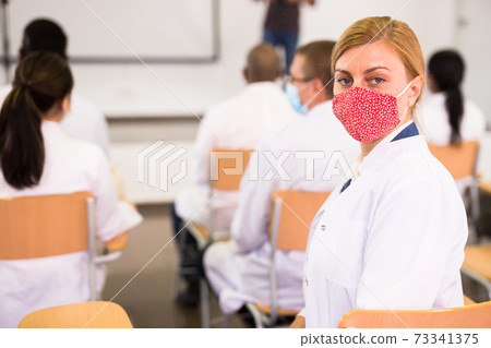 Woman in protective mask participating medical seminar in conference room Woman in protective mask participating medical seminar in conference room 73341375