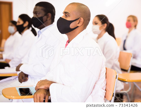 Hispanic doctor in protective mask attending medical congress Hispanic doctor in protective mask attending medical congress 73341426