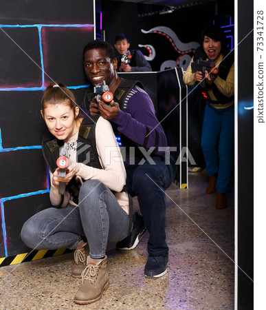 Multiracial couple playing lasertag Multiracial couple playing lasertag 73341728