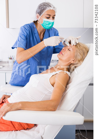 Woman during beauty facial injections Woman during beauty facial injections 73342108