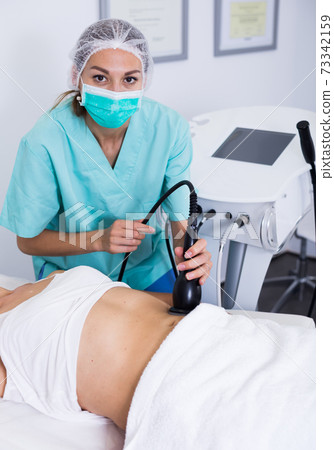 Beautician doing cryoliposuction 73342159