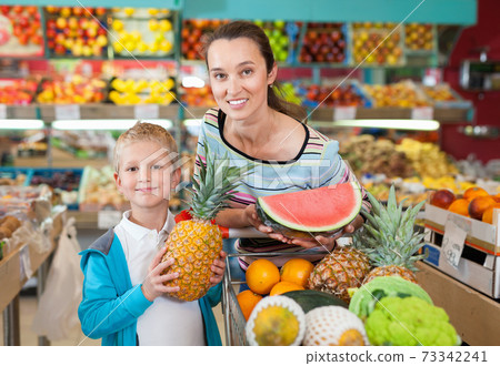 Little boy with his mother choosing fresh fruits and vegetables at supermarket 73342241