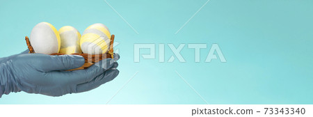 Easter in gloves. The family shares Easter eggs in protective gloves and a mask. Coronavirus, Quarantine, Pandemic Easter in gloves. The family shares Easter eggs in protective gloves and a mask. Coronavirus, Quarantine, Pandemic 73343340