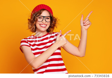 Cheerful stylish woman pointing away Cheerful stylish woman pointing away 73343816