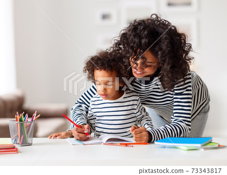 Ethnic mother helping son with homework assignment 73343817