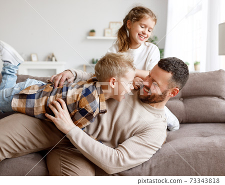 Kids playing with father on sofa 73343818