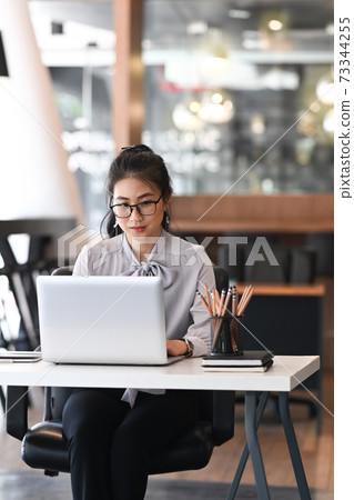 Portrait of businesswoman working on laptop computer at modern workplace. Portrait of businesswoman working on laptop computer at modern workplace. 73344255