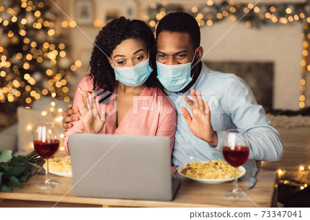 Black couple in masks waving to laptop 73347041