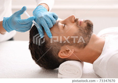 Middle-aged man having hair treatment at beauty salon 73347670