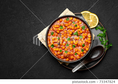 Chana Masala or Chole in black bowl. Indian cuisine veg chickpeas curry dish. Asian vegetarian food Chana Masala or Chole in black bowl. Indian cuisine veg chickpeas curry dish. Asian vegetarian food 73347824