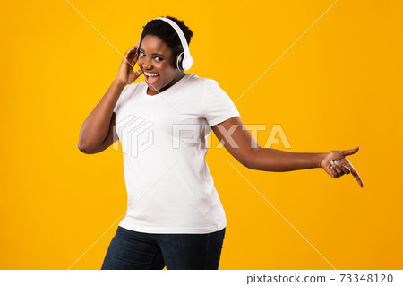 Overweight Black Lady Listening Music In Headphones Over Yellow Background 73348120