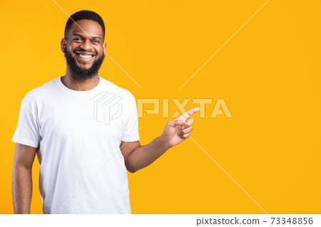 Black Man Pointing Finger Aside Standing Over Yellow Studio Background Black Man Pointing Finger Aside Standing Over Yellow Studio Background 73348856