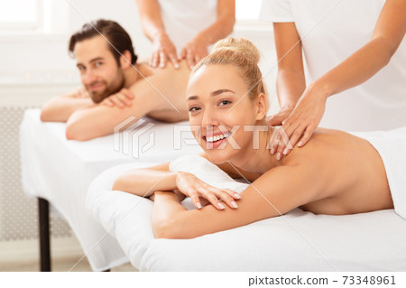 Cheerful Spouses Receiving Relaxing Back Massage Lying Indoor 73348961