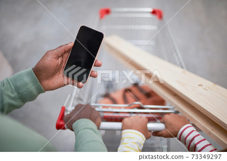 African-American Man Holding Smartphone in Supermarket Closeup 73349297