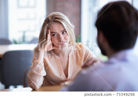 Young Caucasian woman disinterested in blind date, feeling bored with conversation at city cafe 73349298