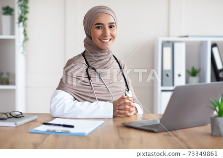 Smiling female doctor muslim woman posing in her cabinet 73349861