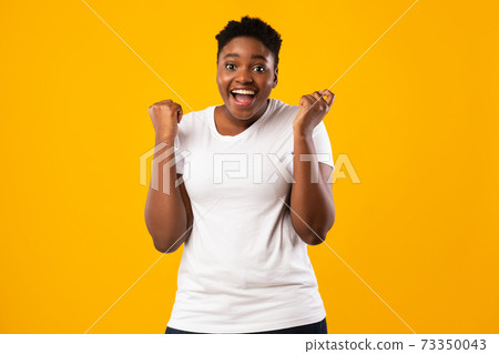Excited Overweight African Lady Shaking Fists Shouting Over Yellow Background Excited Overweight African Lady Shaking Fists Shouting Over Yellow Background 73350043
