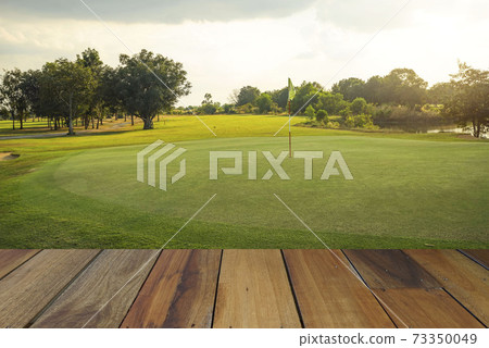 Wooden floor and golf course background. Fresh spring green golf course with wood floor. Beauty natural background, Empty wooden deck table with Green background. 73350049