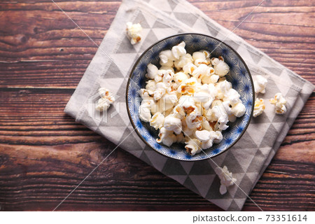 popcorn in a bowl on wooden desk 73351614