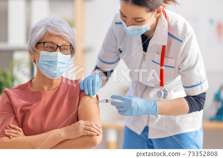 Doctor giving a senior woman a vaccination Doctor giving a senior woman a vaccination 73352808