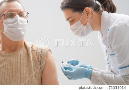 Doctor giving a senior man a vaccination 73353084
