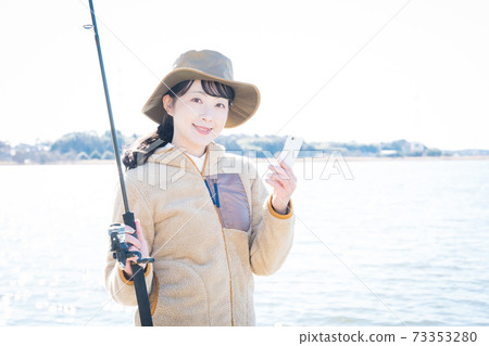 A woman using a smartphone at a fishing spot 73353280