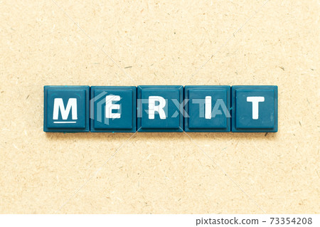 Tile alphabet letter in word merit on wood background 73354208