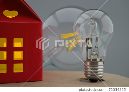 Light bulb and small house with warm light 73354235