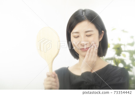 Beauty image A woman who smiles with her hands on her cheeks 73354442