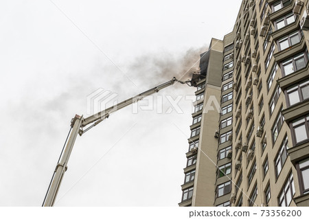 fire engine trucks with ladder at accident in highrise tower residential apartment or office building in city center. Firefighter brigade elevated on platform. Emergency rescue at disaster 73356200