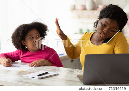 Busy Working African American Mother Ignoring Her Little Daughter Asking For Attention 73356639