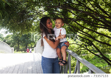 young pretty brunette mother with little cute boy walking in park happy smiling, lifestyle people concept young pretty brunette mother with little cute boy walking in park happy smiling, lifestyle people concept 73357133