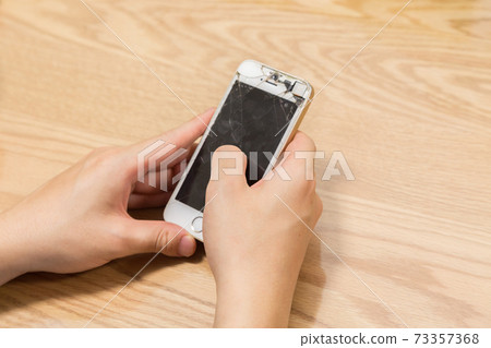 A man's hand operating a broken smartphone A man's hand operating a broken smartphone 73357368