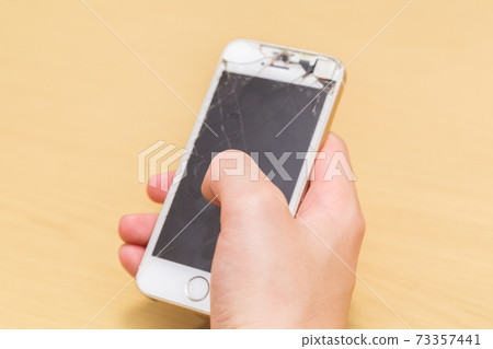 A man's hand operating a broken smartphone A man's hand operating a broken smartphone 73357441