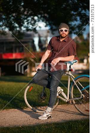 A handsome male with bicycle and backpack 73357513