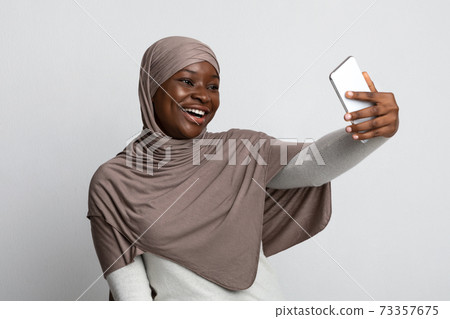 Joyful Black Muslim Lady In Hijab Taking Selfie On Smartphone Joyful Black Muslim Lady In Hijab Taking Selfie On Smartphone 73357675