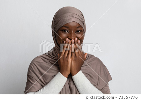 Laughter. Positive Black Muslim Woman In Hijab Covering Mouth With Hands Laughter. Positive Black Muslim Woman In Hijab Covering Mouth With Hands 73357770