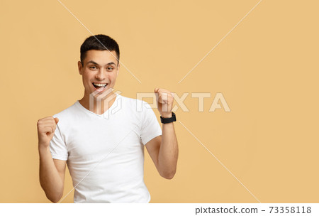 Excited happy student screams with happiness, celebrates his greatest triumph and victory 73358118